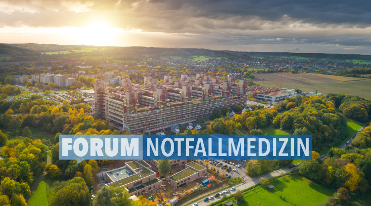 Das Bild zeigt das Uniklinikum Aachen als Luftaufnahme. Auf der Luftaufnahme ist das Logo des Forum Notfallmedizin in weißer Schrift und einer in zwei Blautoenen gehaltenen Sprechblase zu sehen.